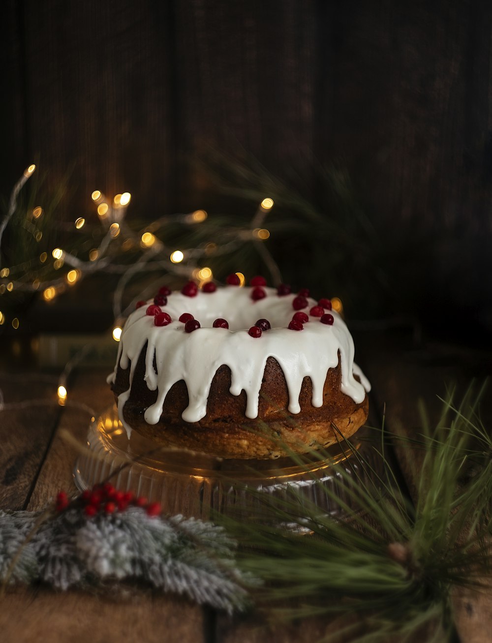 a bundt cake with white icing and pomegranates on a