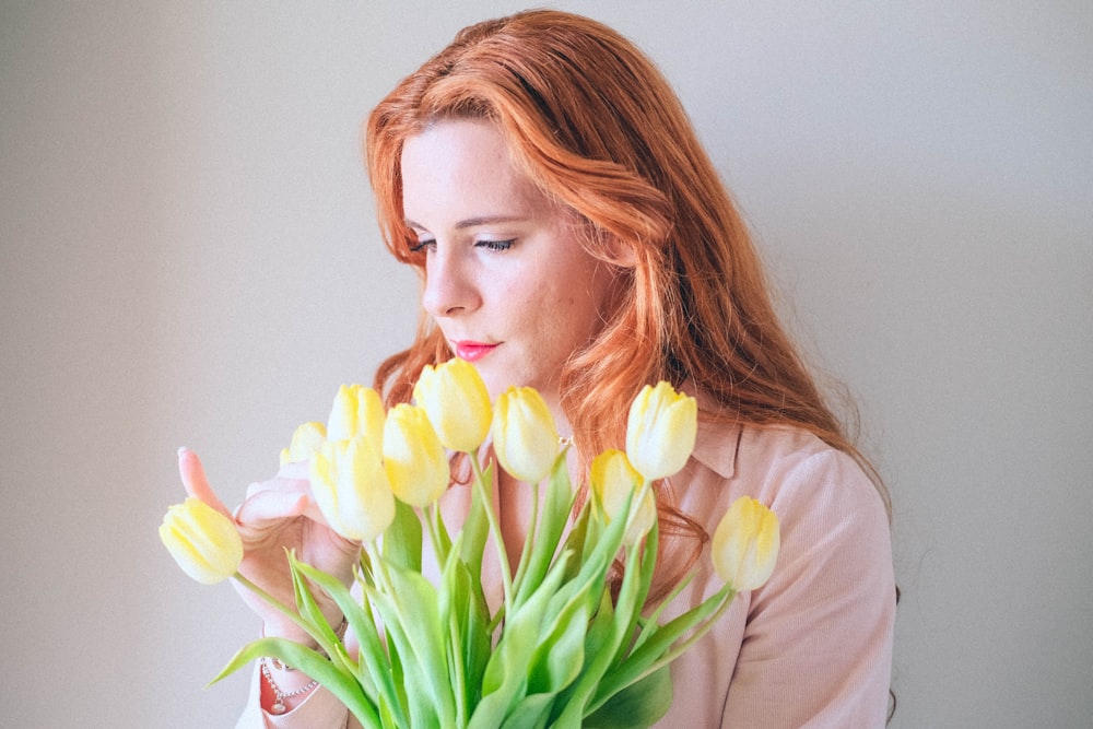 a woman holding a bouquet of yellow tulips