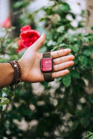 a person's hand holding a small red object