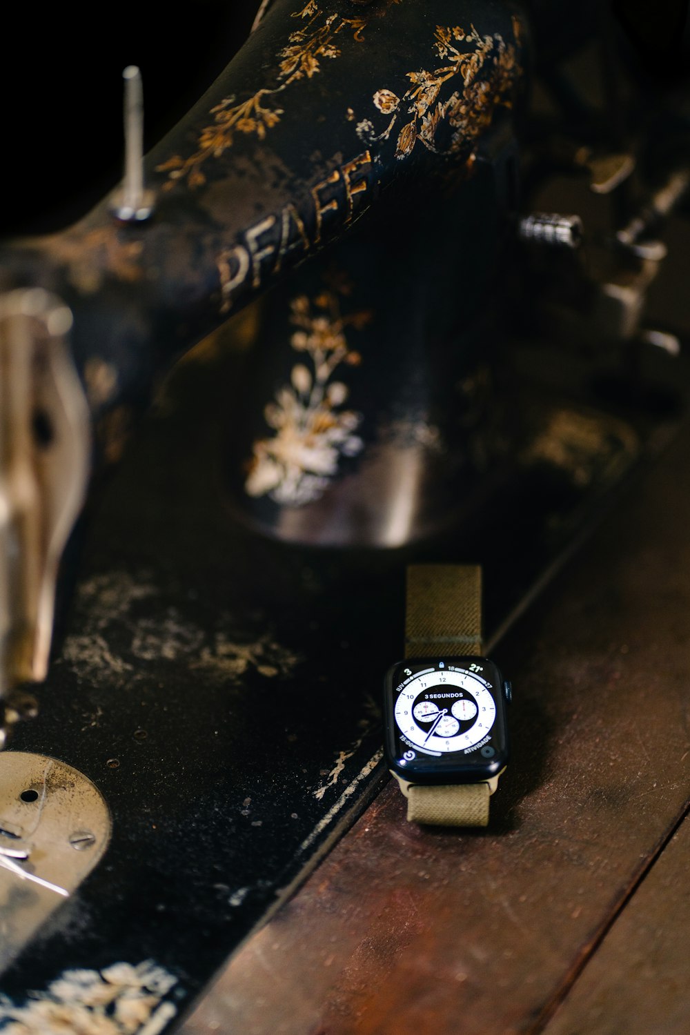 a watch sitting on a table next to a sewing machine