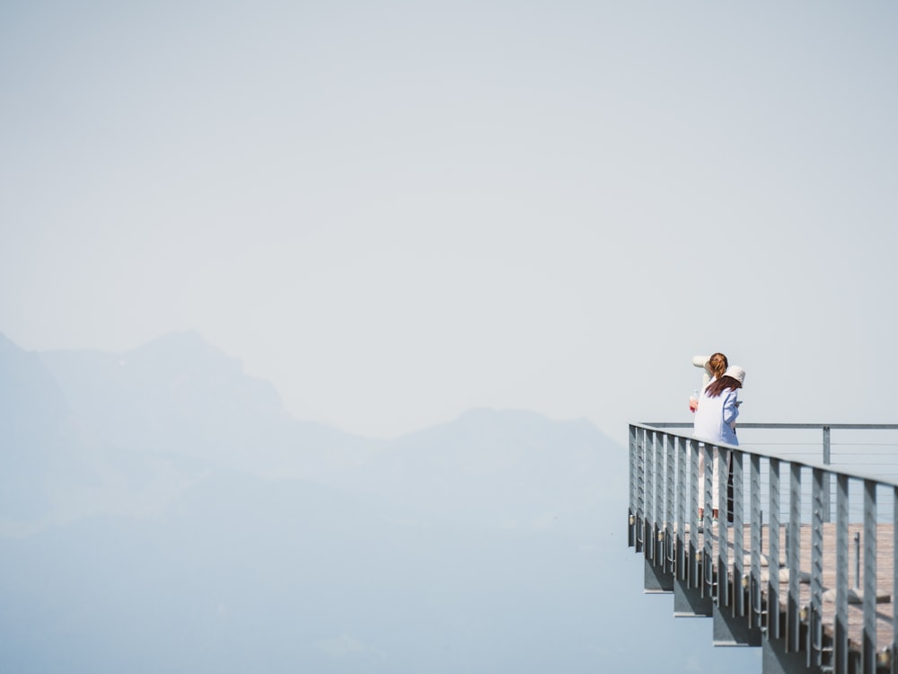 a woman standing on top of a wooden bridge