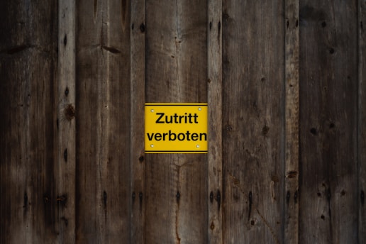 a wooden fence with a yellow sign on it