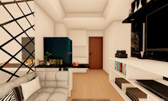 A modern living room with a minimalist design featuring a black and white color scheme. A plush gray sofa is positioned near a wall with a geometric lattice pattern. The room includes a small bar area with decorative bottles and green plants. A sleek TV is mounted on a black marble accent wall, with a shelf below holding books and storage boxes. A wooden door is in the background, along with a compact kitchen area with dark cabinetry.