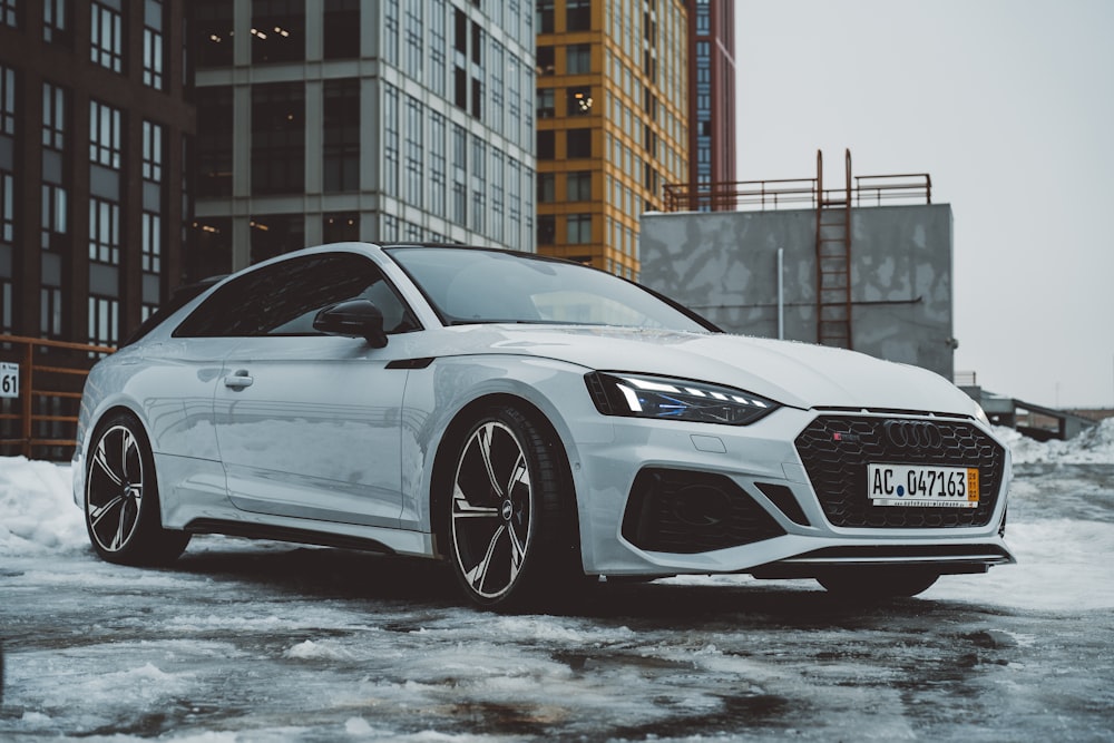 a white car parked in front of a tall building