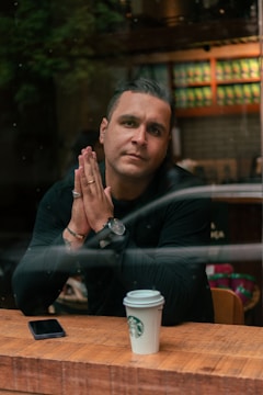 Close-up of hands typing questions on a smartphone in a coffee shop.