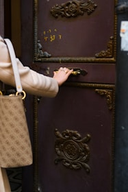 a woman opening a door with a handbag
