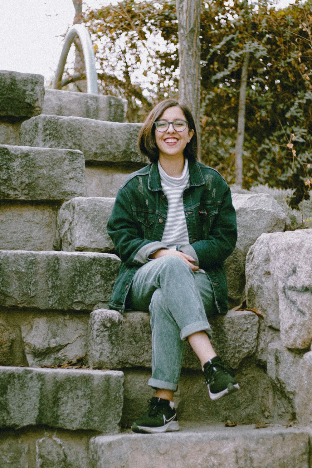 a woman sitting on a stone wall with her legs crossed