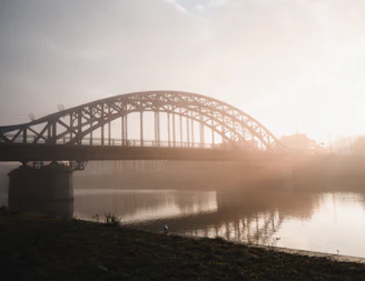 A sweeping aerial shot of the iconic Linen Bridge spanning a misty Irish river at dawn.