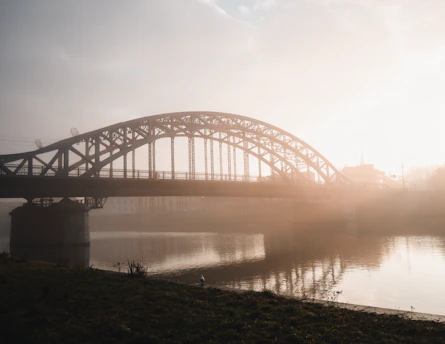 A sweeping aerial shot of the iconic Linen Bridge spanning a misty Irish river at dawn.