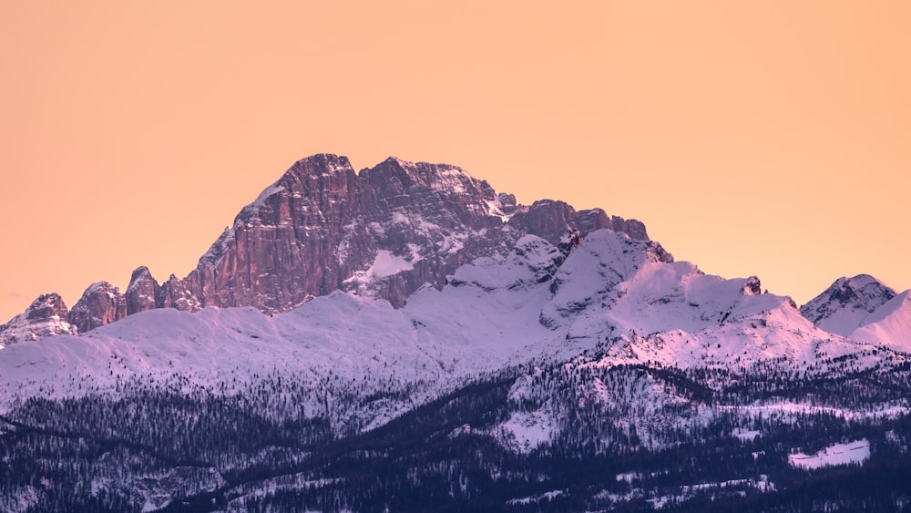 a snow covered mountain with a pink sky