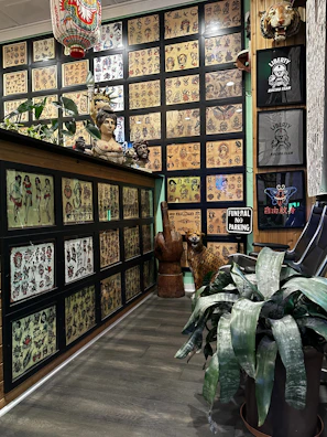 Gallery wall showcasing framed neo-tribal tattoo designs and ceramic art under soft lighting.