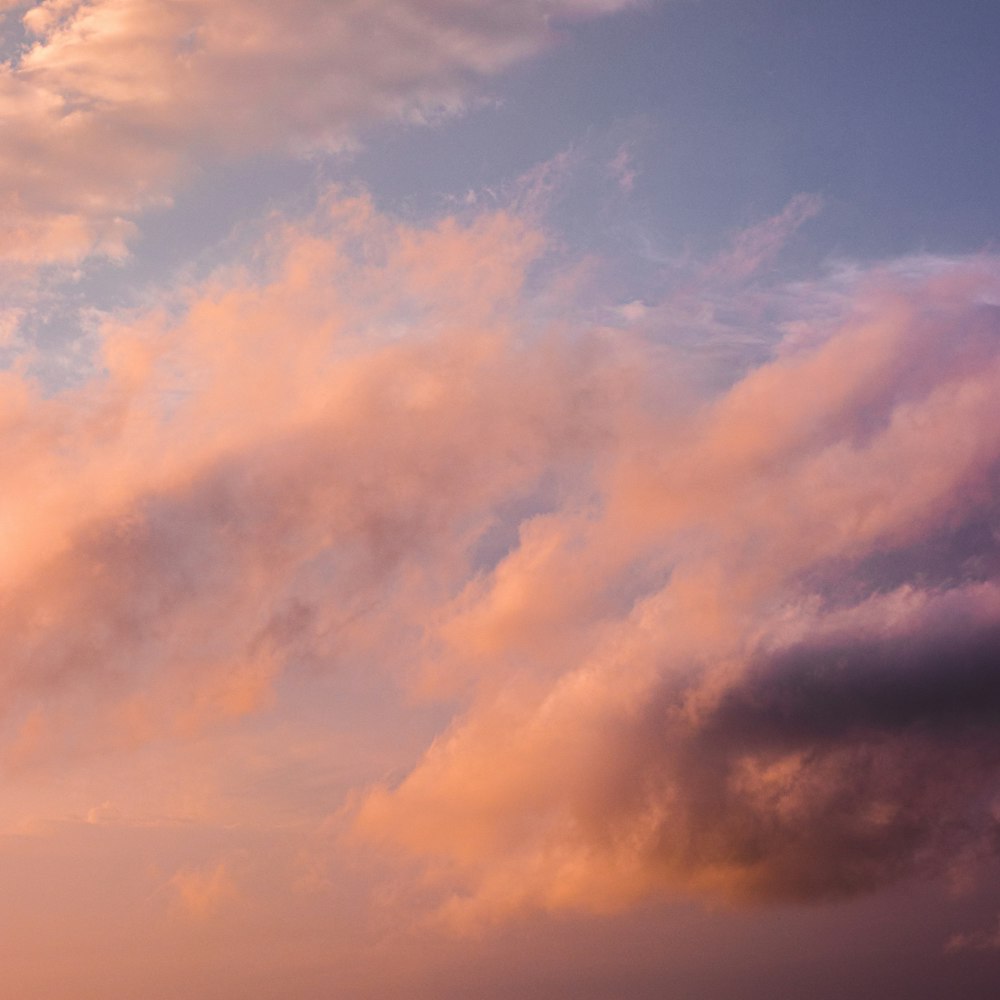 a plane flying through a cloudy sky at sunset