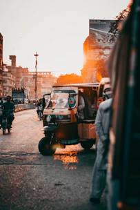 A delivery truck moving through a busy Indian city street at sunset.