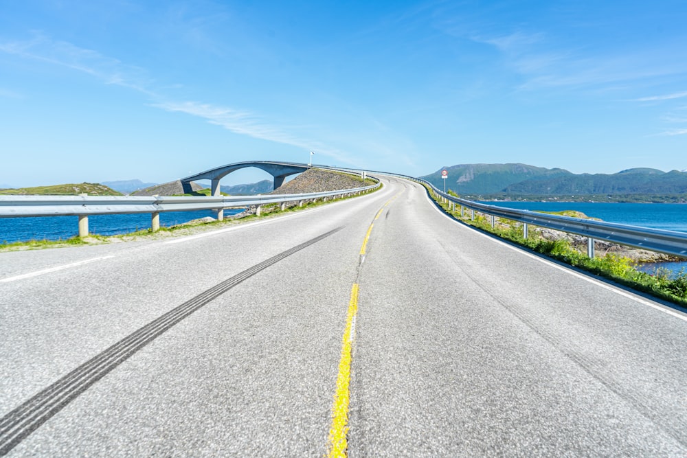 an empty road with a bridge in the background