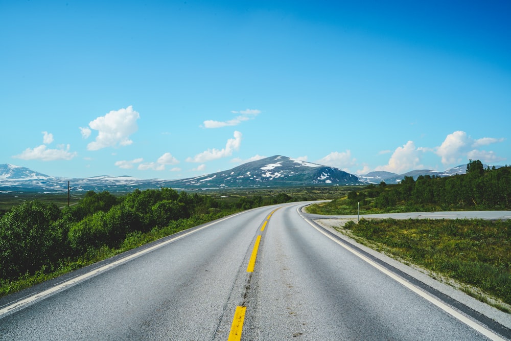 an empty road with mountains in the background