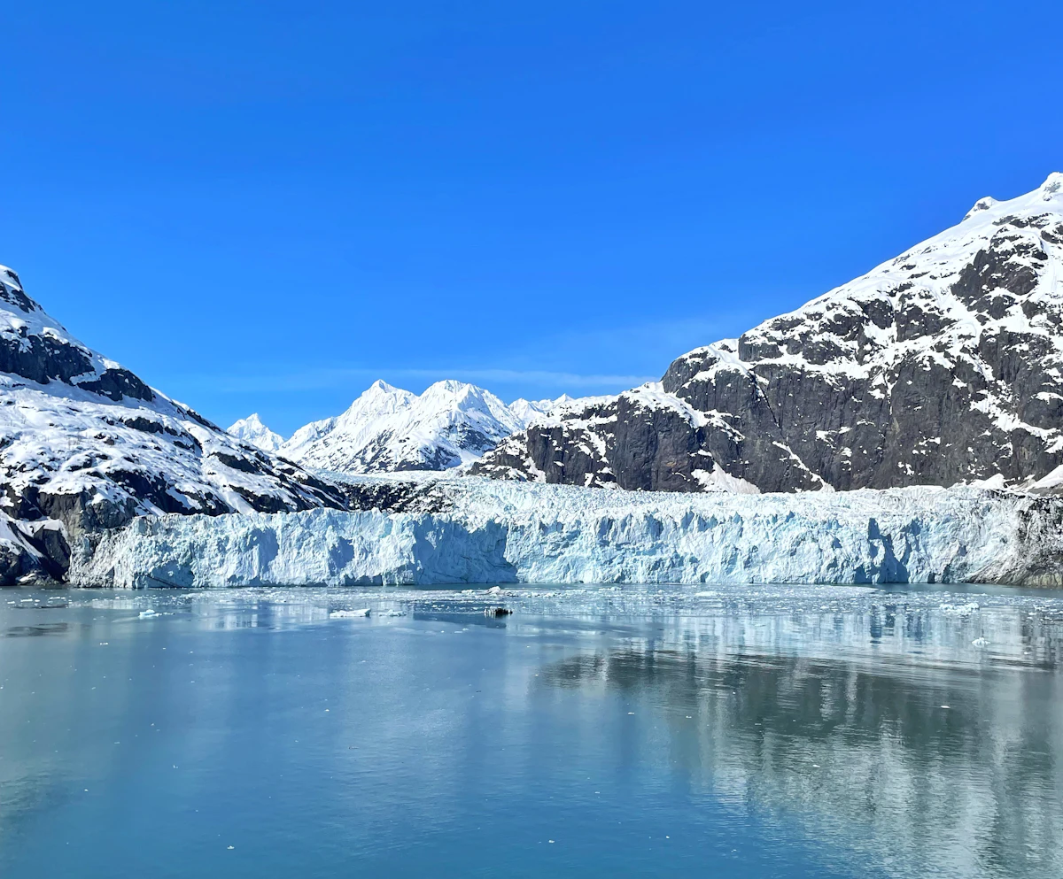 A tidewater glacier beneath snowy peaks