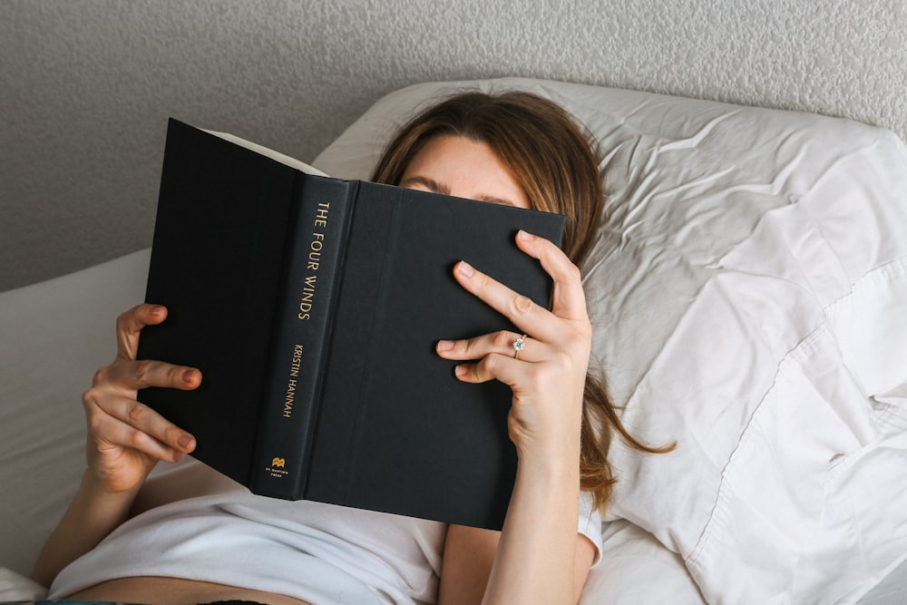 a woman laying in bed reading a book