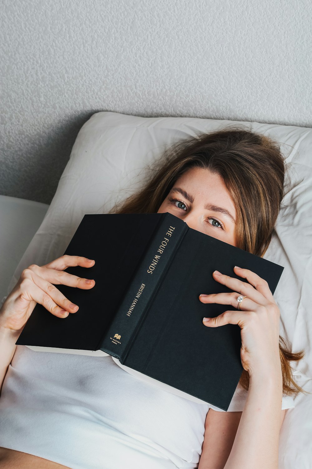 a woman laying in bed with a book in her hands