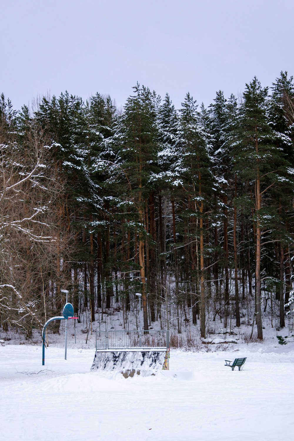 a park bench sitting in the middle of a snow covered field