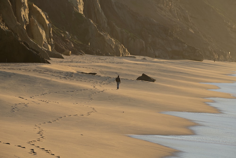 a person walking on a beach with footprints in the sand