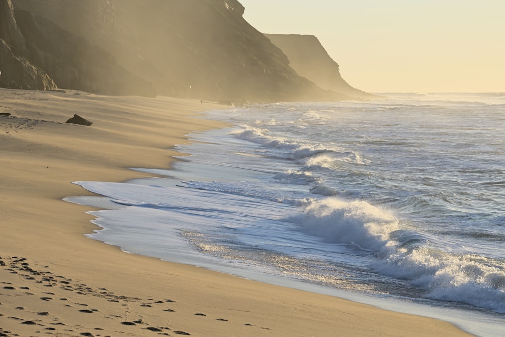 a sandy beach with waves coming in to the shore