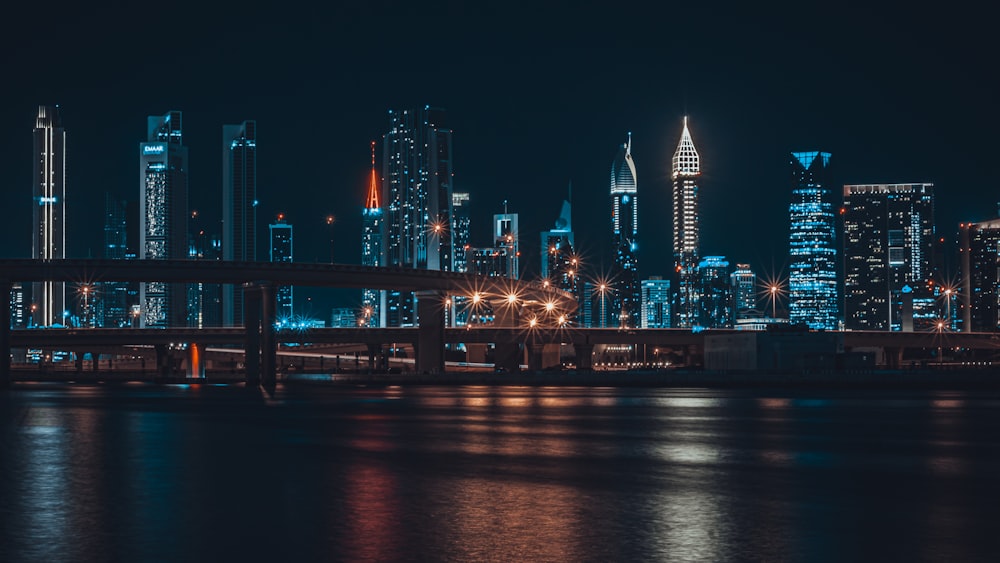 a city skyline at night with lights reflecting off the water