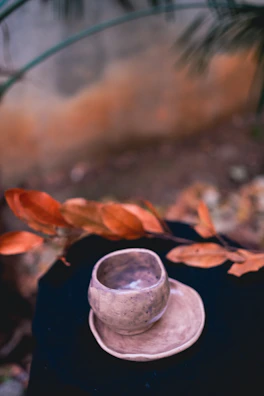 A vibrant handmade ceramic cup with warm orange glaze on a wooden table
