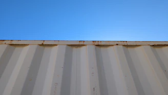 A sturdy 20-foot shipping container placed in an open industrial yard under a clear sky.