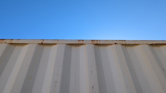 A sturdy 40-foot shipping container with double doors open, set against a clear blue sky at an industrial site.