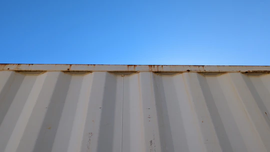 A sturdy 20-foot shipping container placed in an open industrial yard under a clear sky.