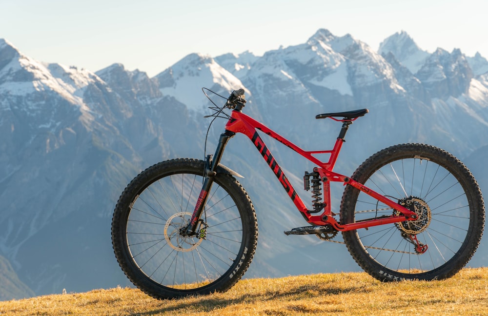 a red mountain bike parked on top of a grass covered hill