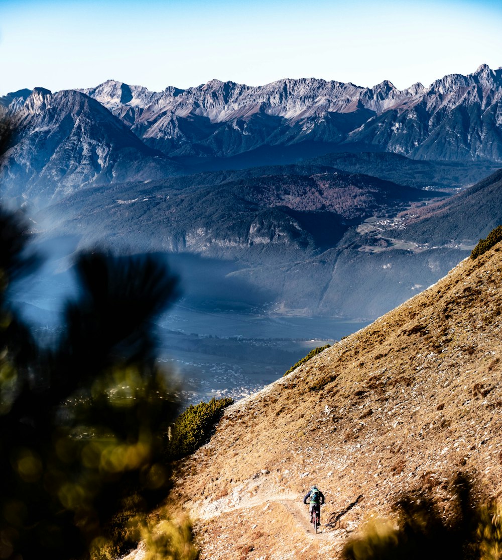 a person walking up a hill with mountains in the background