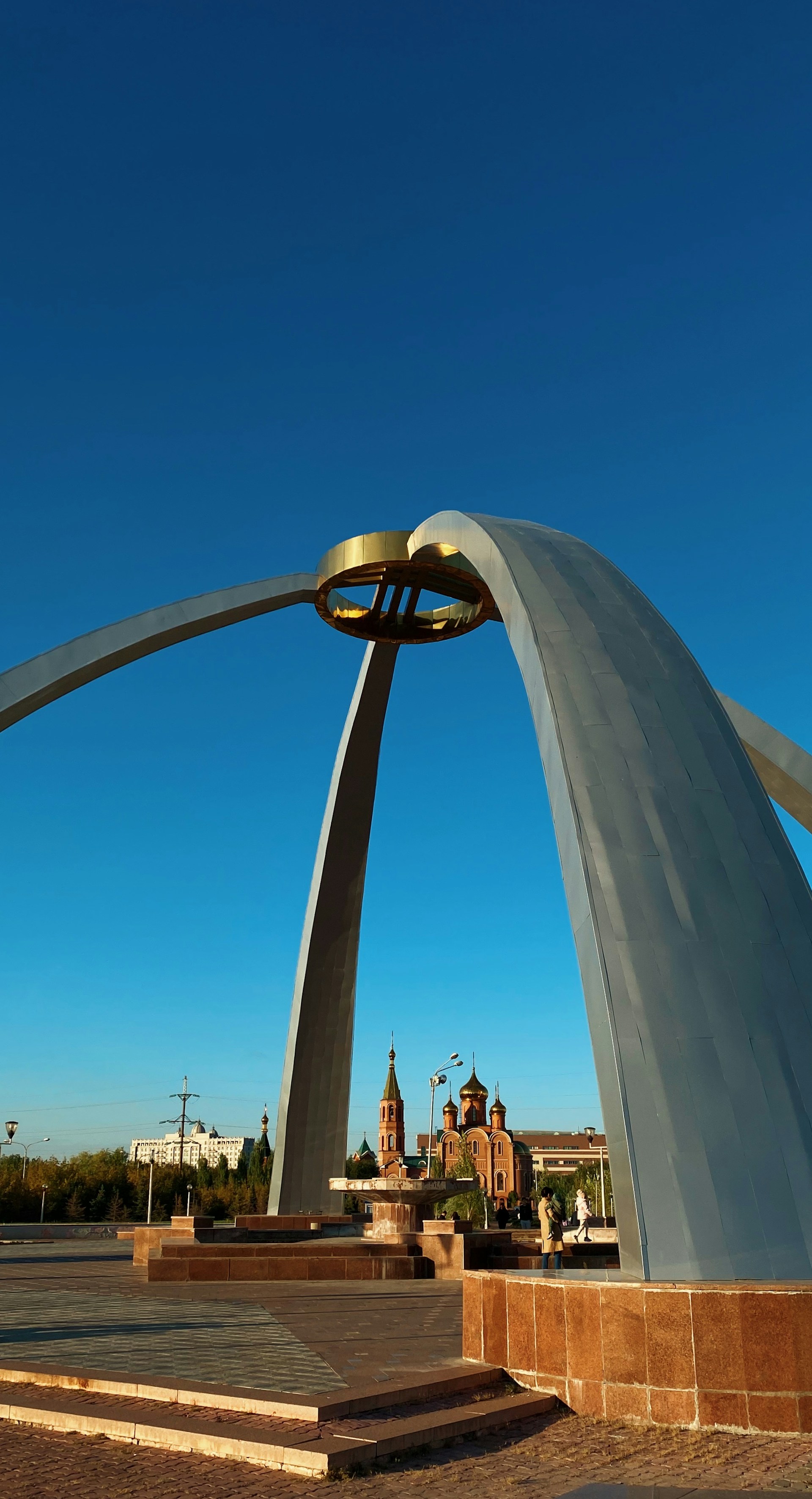 a large metal arch with a clock tower in the background