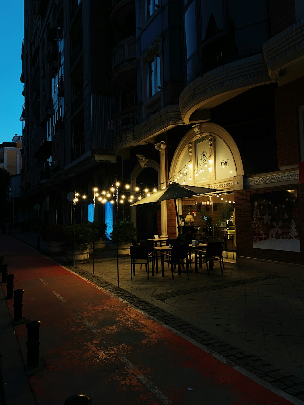 a dark street with tables and umbrellas lit up at night