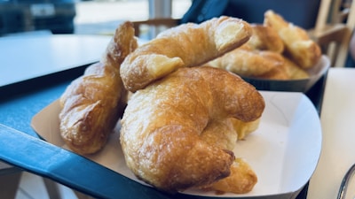 Close-up of golden croissants stacked on a rustic wooden tray.