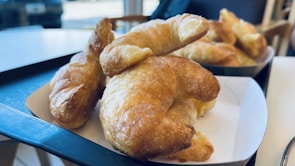A warm tray of flaky croissants and pain au chocolat cooling on a wooden table.