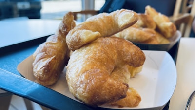 Close-up of freshly baked golden croissants stacked on a wooden tray, with soft morning light streaming in.