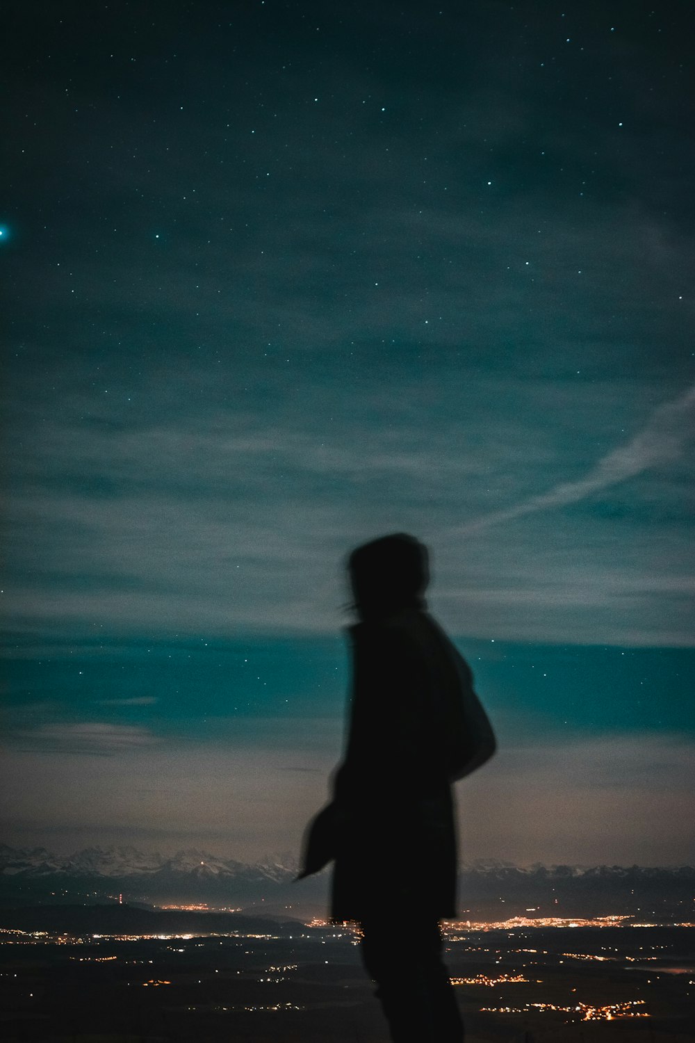 a man standing on top of a hill under a night sky