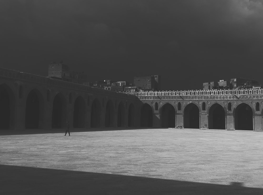 a black and white photo of a person standing in a courtyard