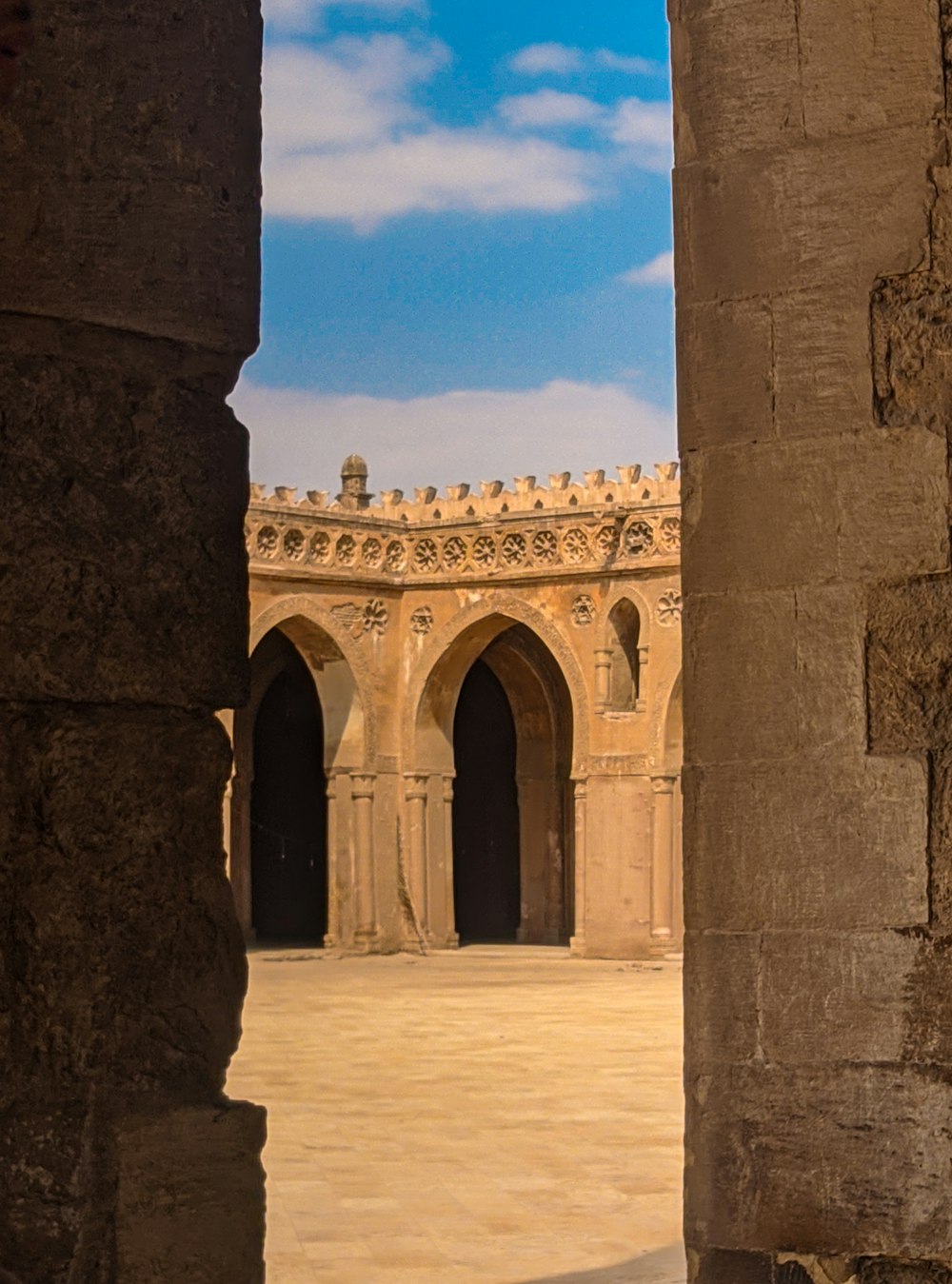 a view of a courtyard through two stone pillars