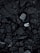 A close-up view of a surface covered in dark, rough asphalt with scattered pieces of white rubble and debris. The texture is uneven and consists of various-sized stones and broken concrete fragments.