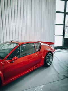 A shiny red sports car parked inside the auto body shop, ready for pickup.