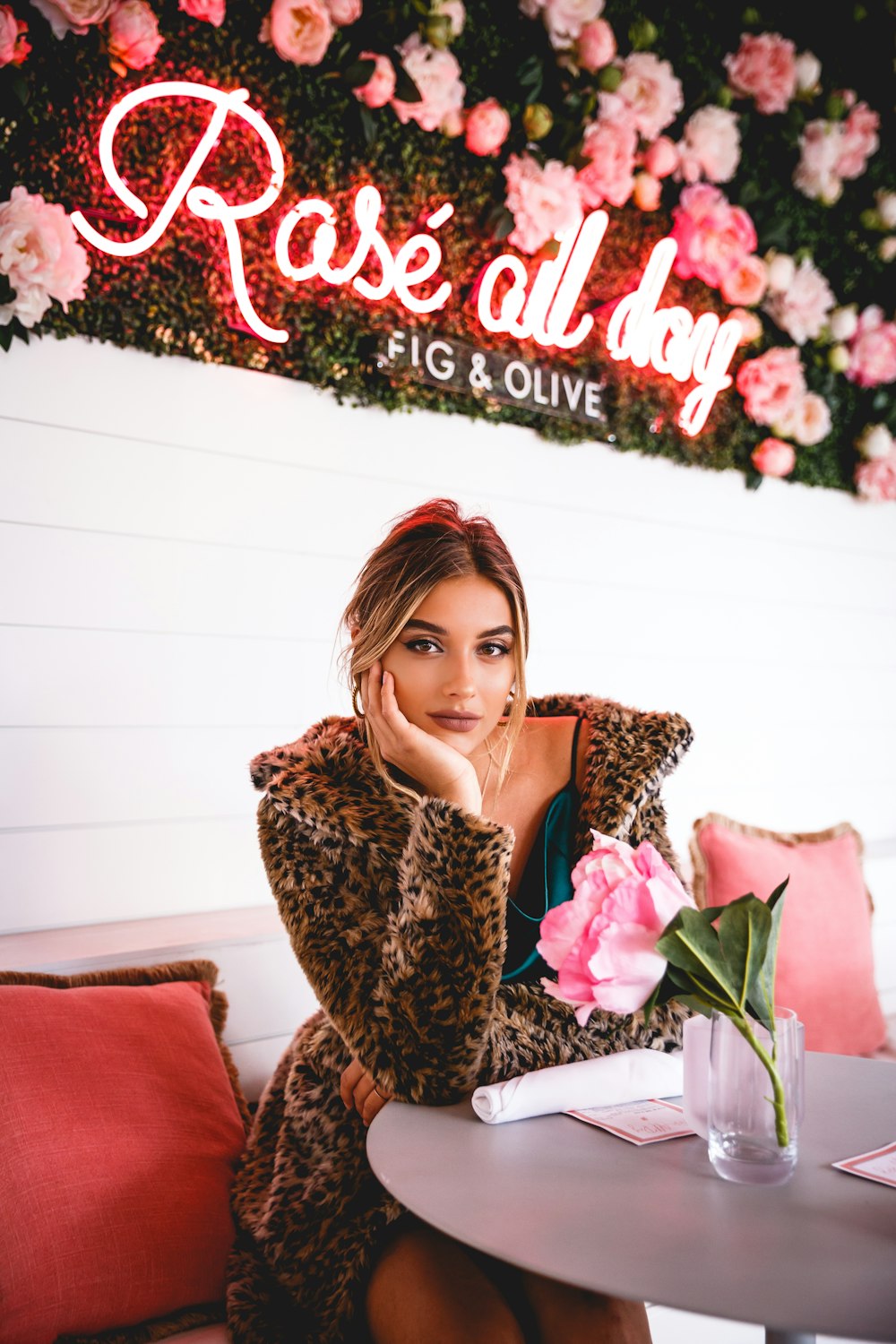 a woman sitting at a table in front of a sign