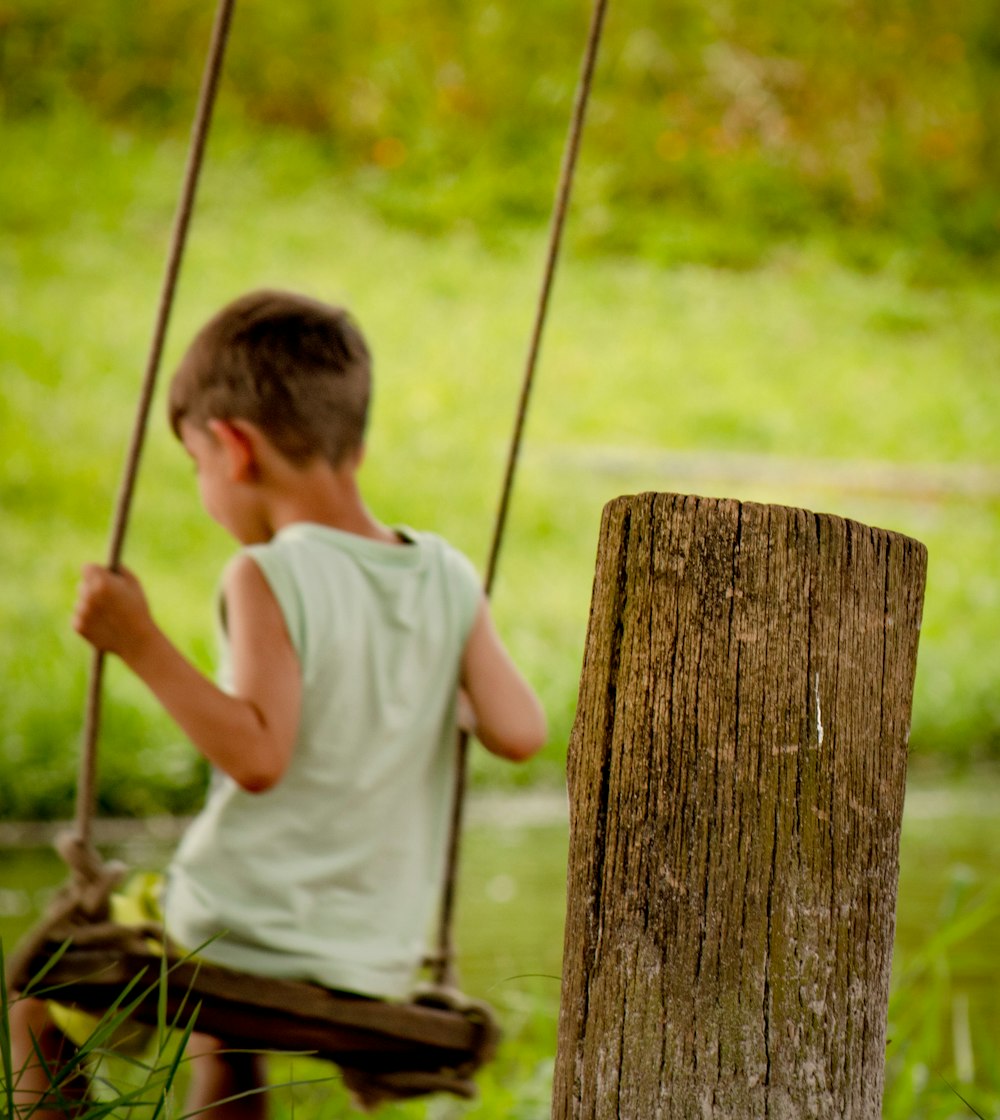 a young boy sitting on a wooden swing