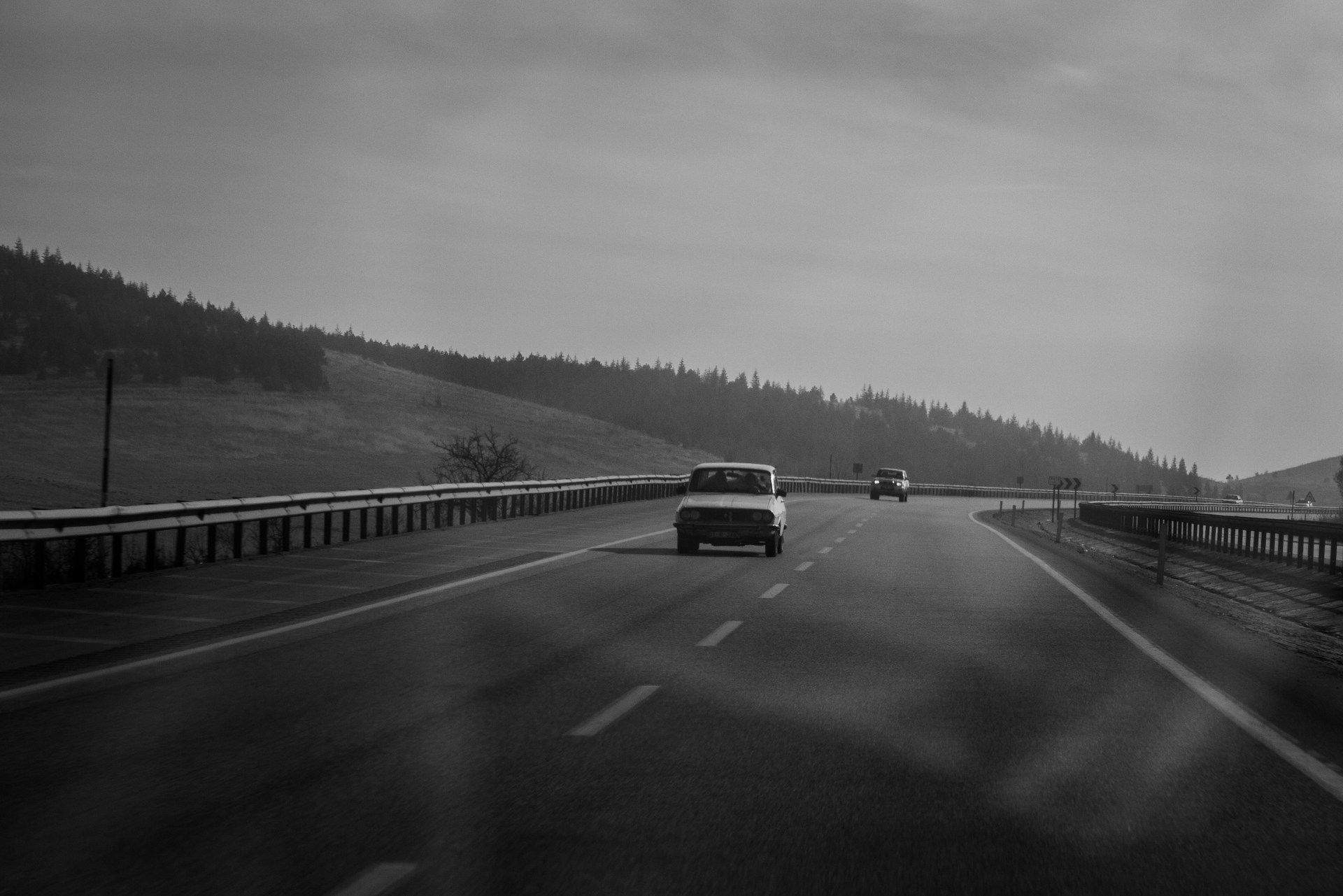 a black and white photo of a car driving down a highway