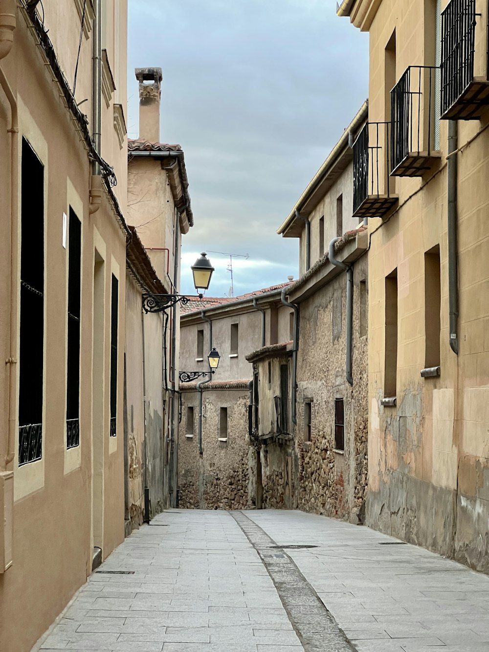 a narrow street with a lamp post in the middle of it