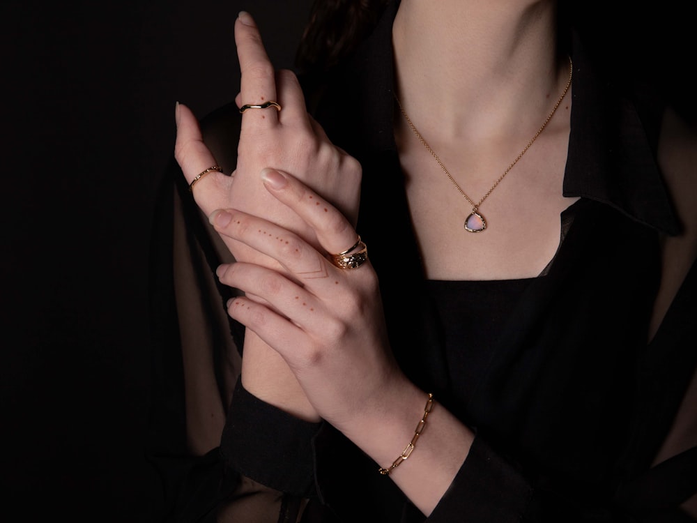 a woman wearing a black shirt and holding her hands together