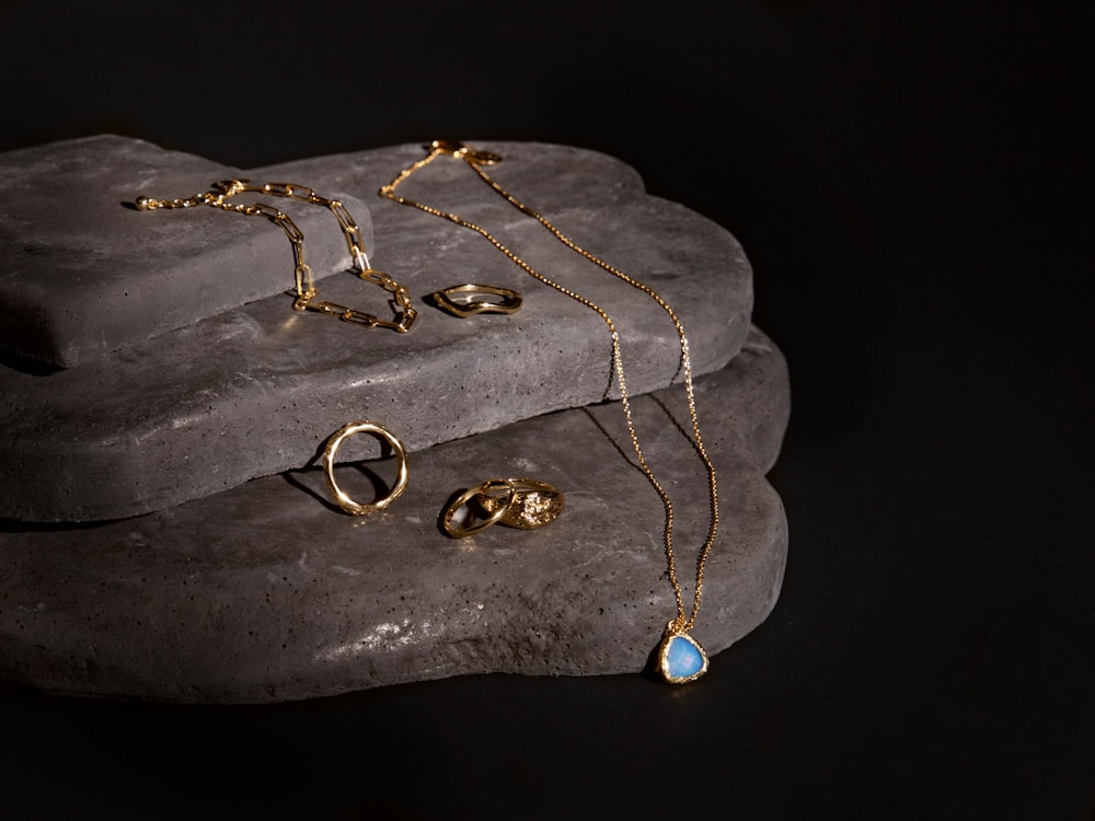 a couple of rings and a necklace on a rock