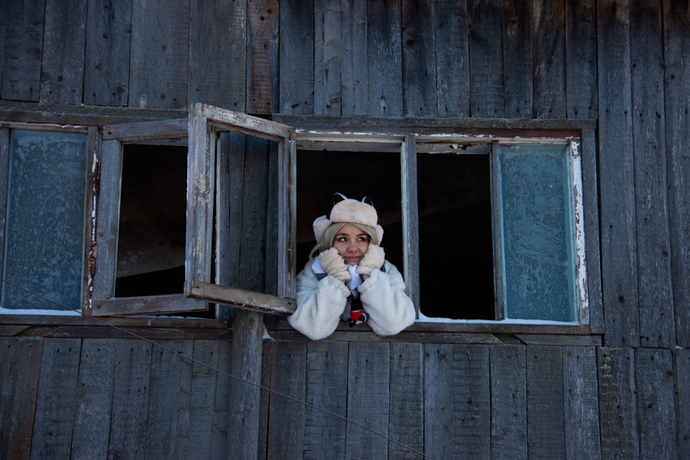 a woman in a fur coat looking out of a window