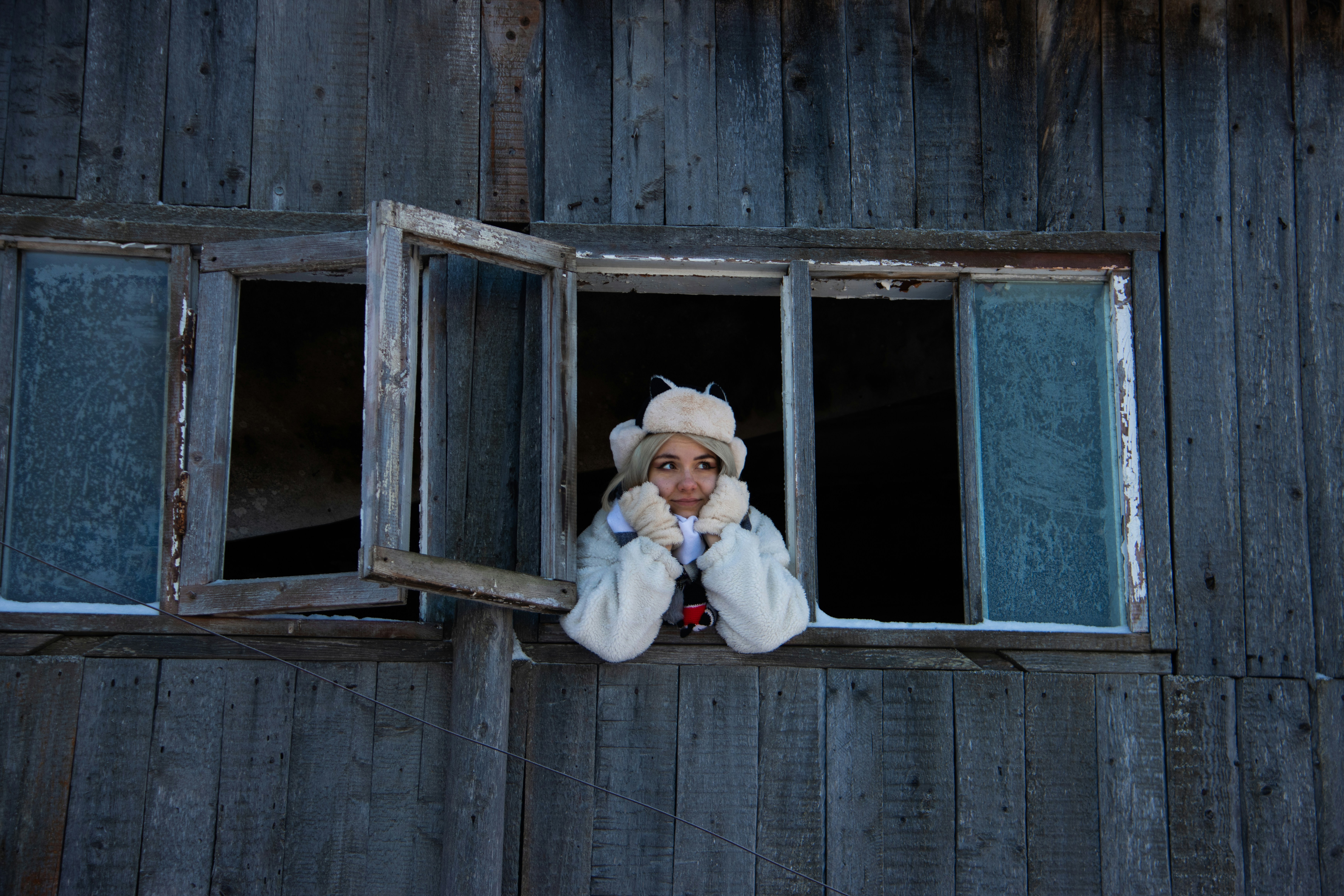 a woman in a fur coat looking out of a window
